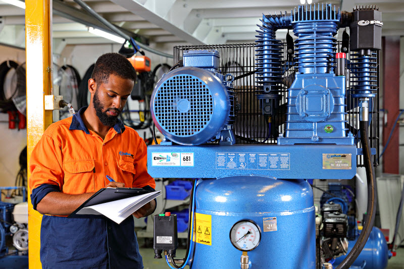 Employee wearing a uniform checking the compressor machines